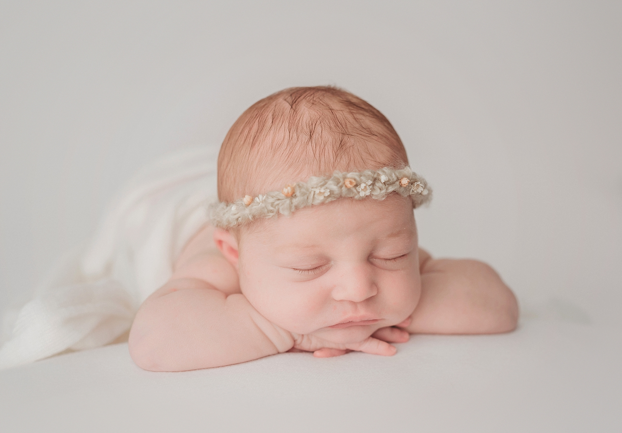Sleeping newborn baby girl posed with floral crown in San Diego photography studio