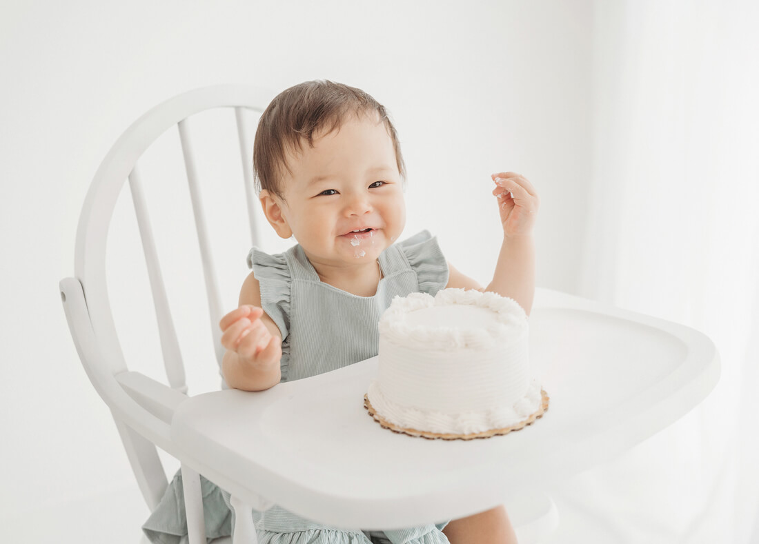 happy little girl smashing her first birthday cake during her carlsbad cake smash photography session