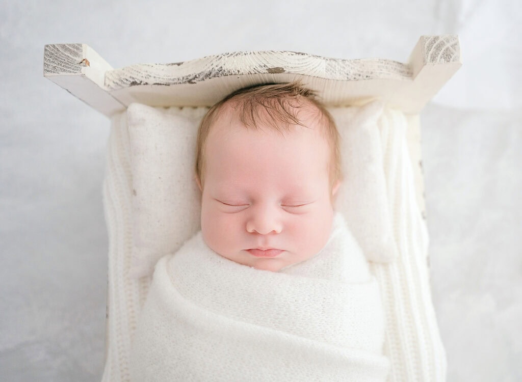 Encinitas Newborn Photography: Timeless Portraits for Your Growing Family 4 Encinitas newborn photography session where the sweet baby is sleeping in a tiny bed