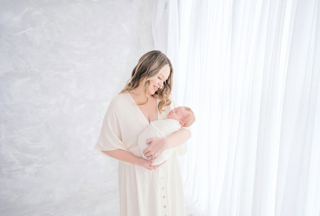 Encinitas Newborn Photography: Timeless Portraits for Your Growing Family 2 Encinitas newborn photographer captures mother holding sleeping newborn baby in studio session